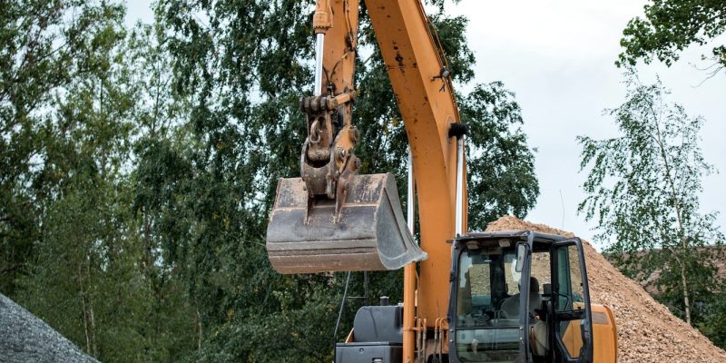 Yellow excavator on gravel pile.